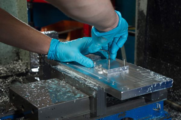 Hands working of materials that are clamped in place. hands have blue medical gloves on. Safety during Covid.